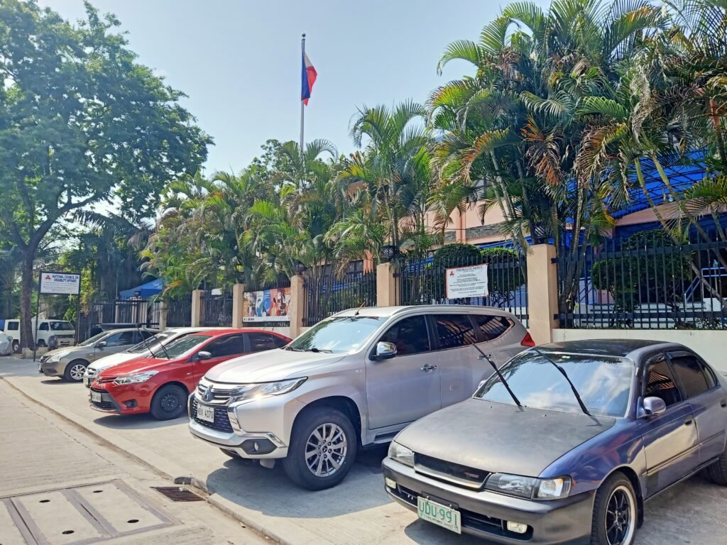 Parking area outside NCDA premises with parked vehicles and facade